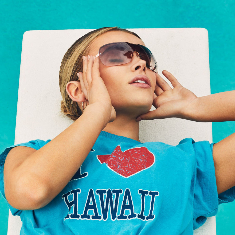 on model - blonde female wearing dime optics wilshire sunglasses with a brushed rose gold frame and rose gradient lenses above the pool