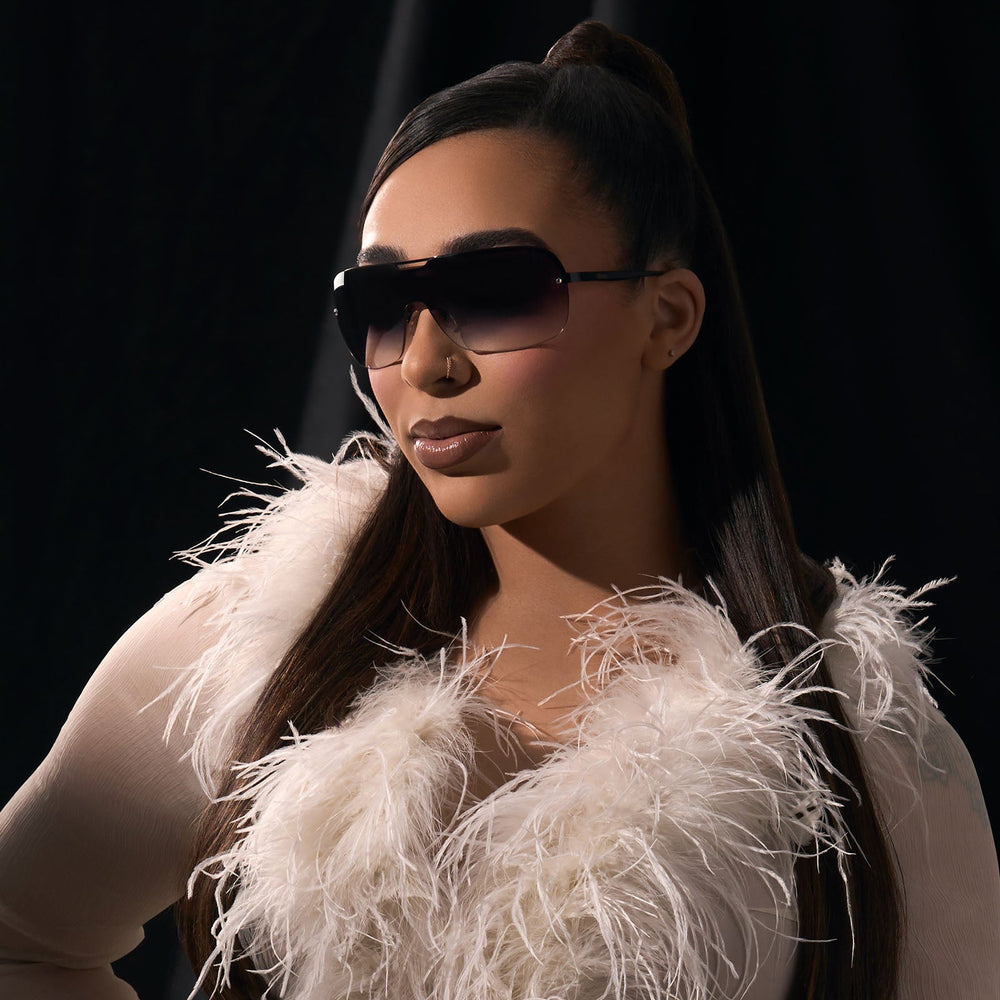 on model - rissa g wearing the rissa g x dime optics bou g shield sunglasses with a black metal frame and grey gradient lenses angled view