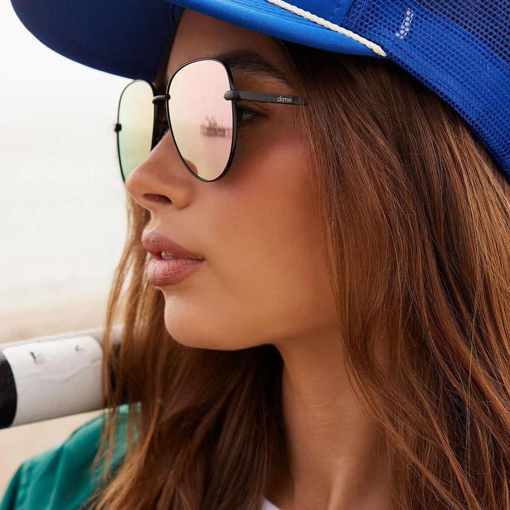 on model - female wearing dime optics abbot aviator sunglasses with a matte black frame and pink mirror polarized lenses side view