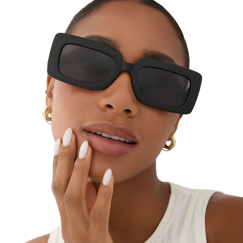 on model - female wearing dime optics featuring the culver rectangular sunglasses with a matte black frame and grey polarized lenses front view