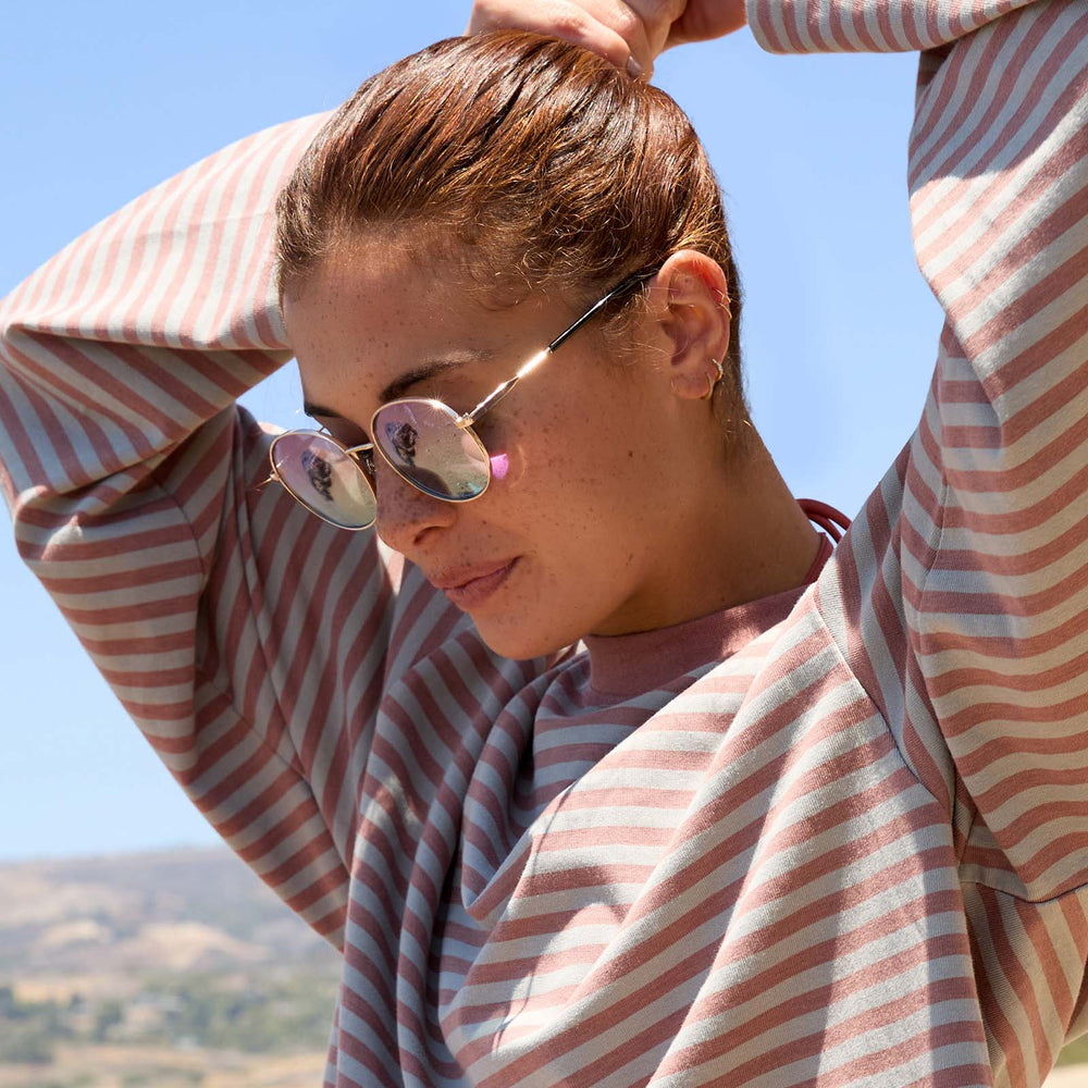 on model - female wearing dime optics featuring the silverlake round sunglasses with a gold frame and wisteria mirror light blue purple lenses side view