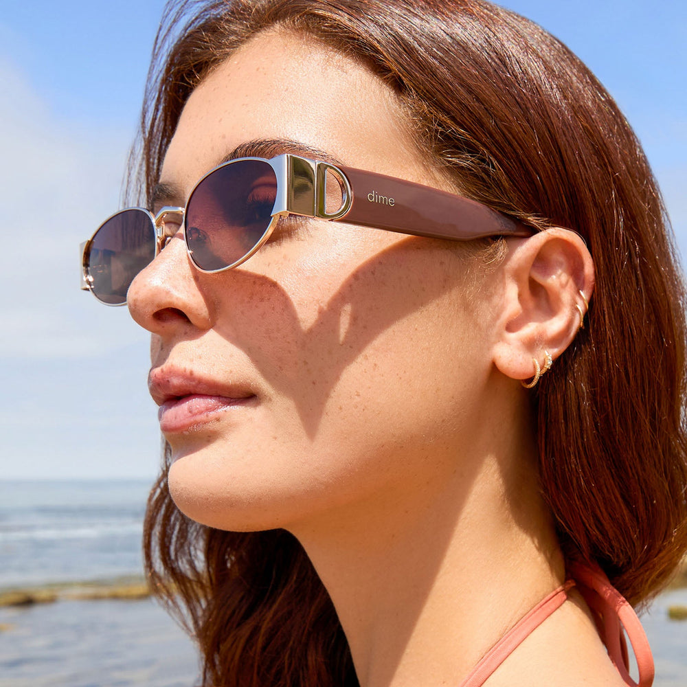 on model - female wearing dime optics featuring the vine rectangular sunglasses with a gold and mocha frame and brown lenses detailed view