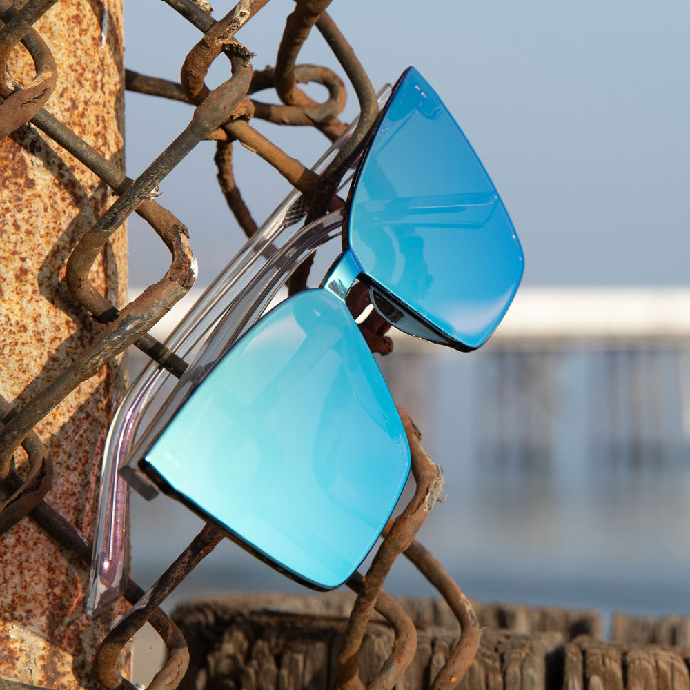 dime optics glendale clear crystal cyan mirror sunglasses hanging on a fence