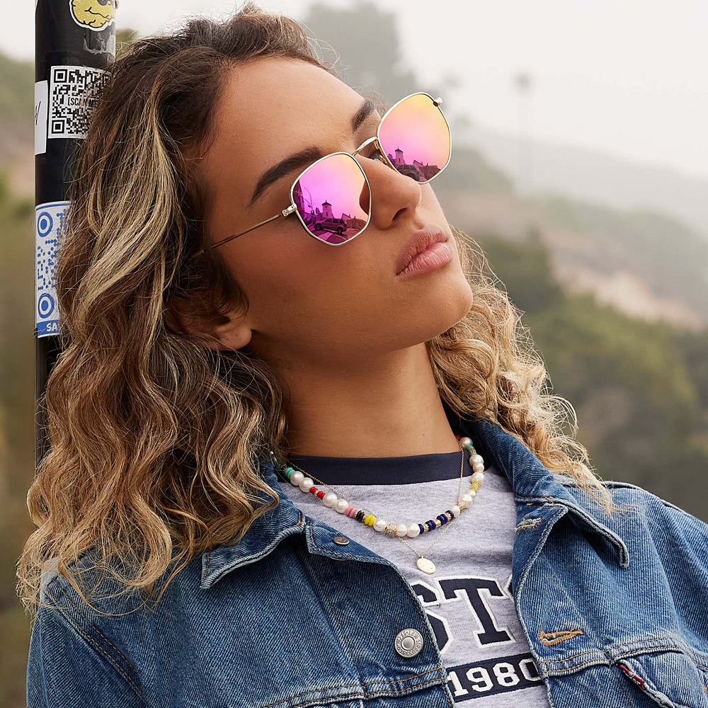 on model - female wearing dime optics roxbury round sunglasses with a gold metal frame and candy pink mirror polarized lenses angled view