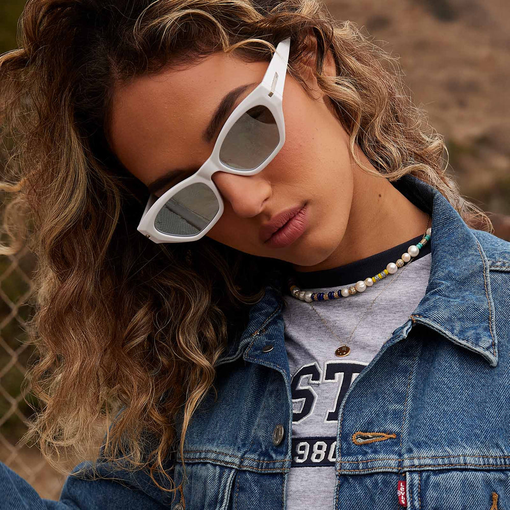 on model - female wearing dime optics sawtelle cat eye sunglasses with a glossy white frame and silver mirror polarized lenses angled view