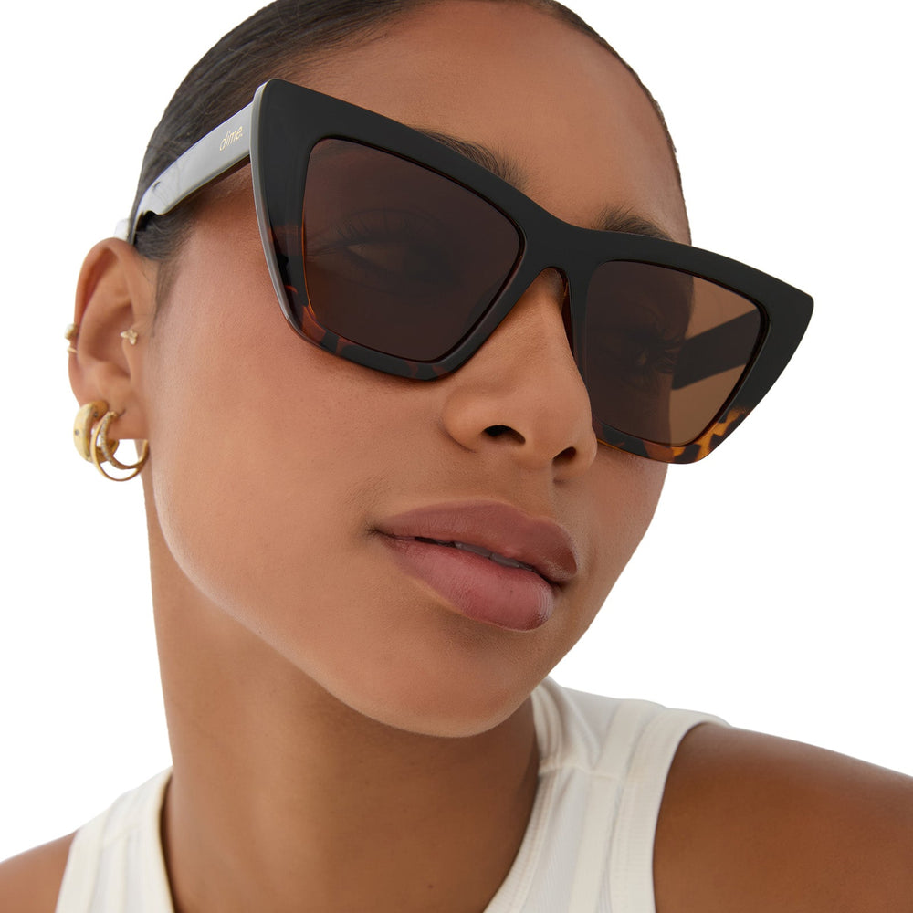 on model - female wearing dime optics featuring the windsor cat eye sunglasses with a black tortoise frame and brown polarized lenses front view