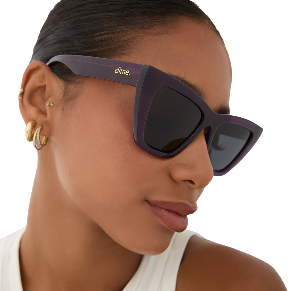 on model - female wearing dime optics featuring the windsor cat eye sunglasses with a amethyst purple frame and grey polarized lenses angled view