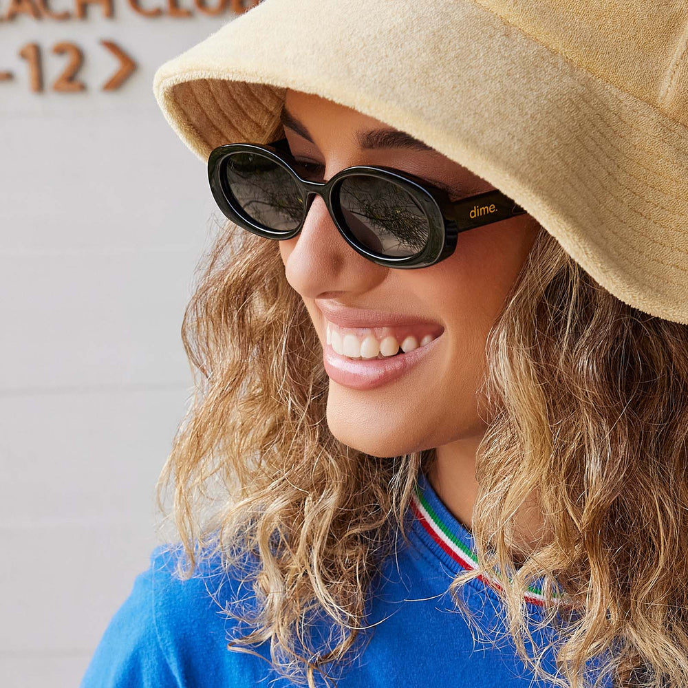 on model - female wearing dime optics westwood round sunglasses with a black frame and grey polarized lenses angled view