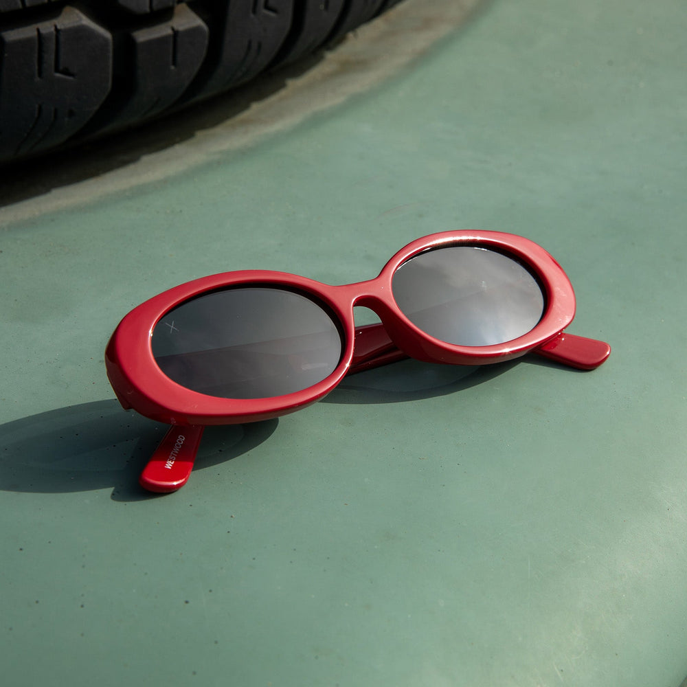 lifestyle - flat lay of dime optics westwood in ruby red grey sunglasses