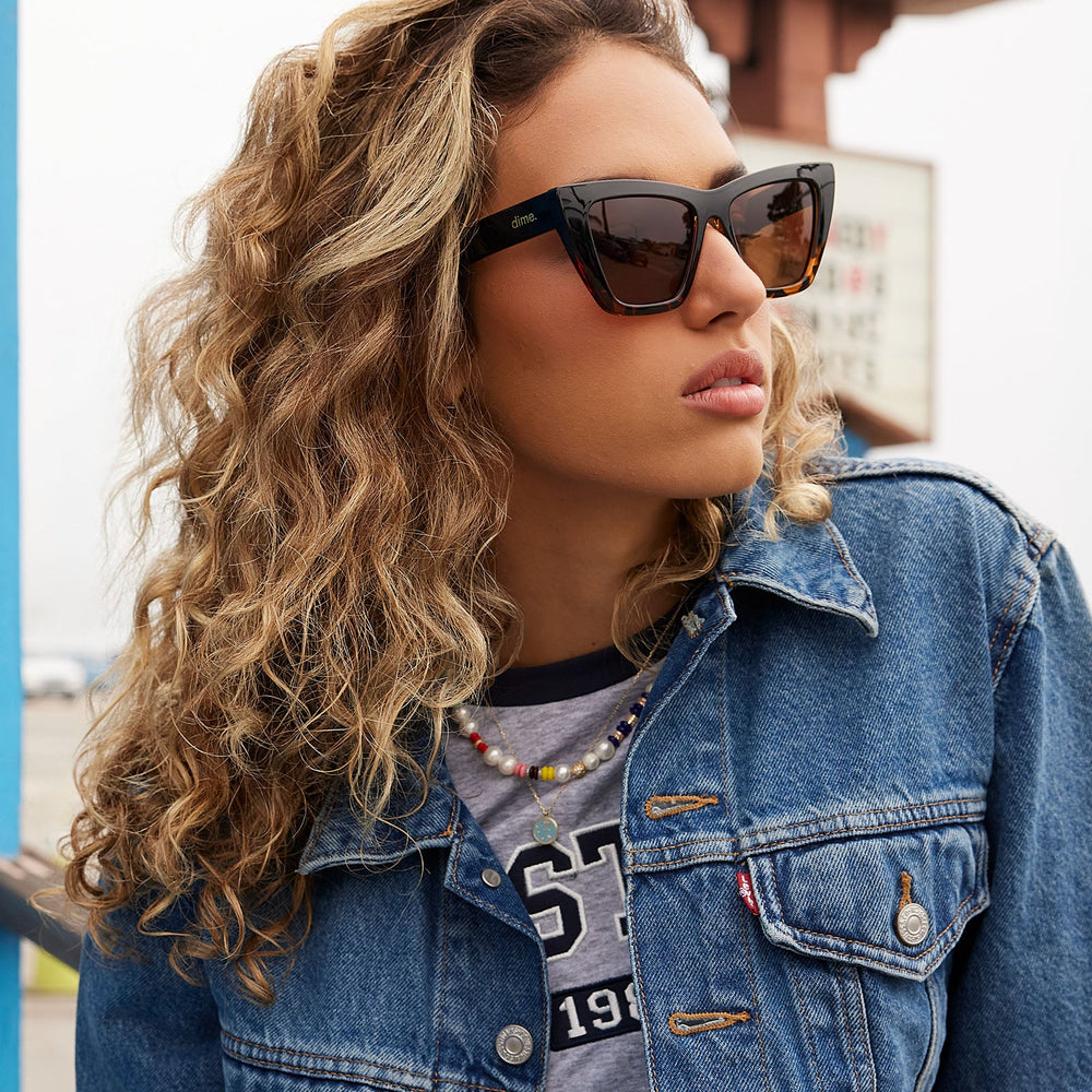 on model - female wearing dime optics featuring the windsor cat eye sunglasses with a black tortoise frame and brown polarized lenses angled view