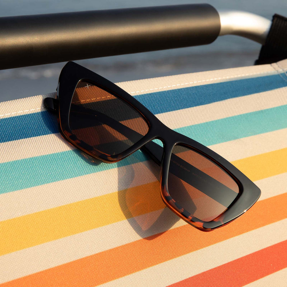 dime optics windsor tortoise sunglasses hanging on a beach chair